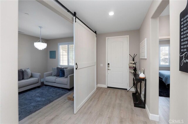 foyer entrance with a barn door and light hardwood / wood-style flooring