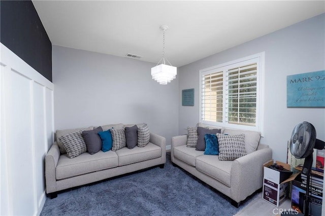 carpeted living room featuring a notable chandelier