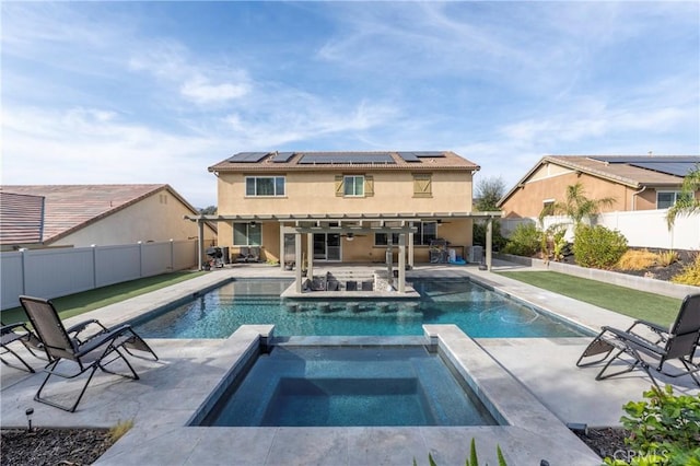 rear view of house with a pool with hot tub, solar panels, and a patio