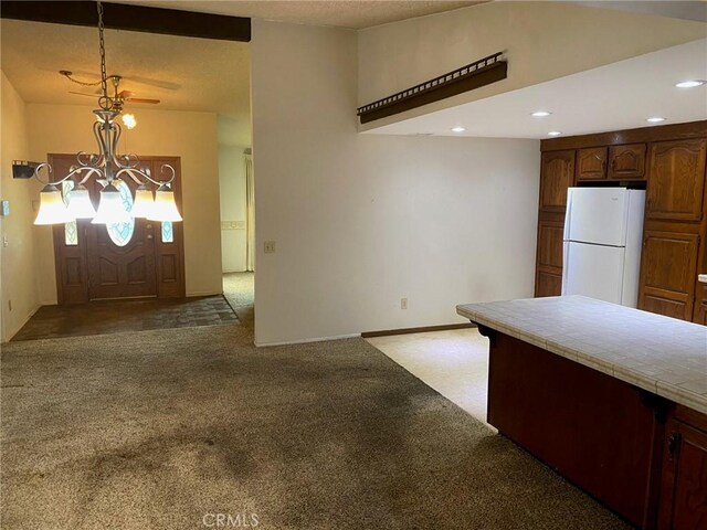 kitchen featuring tile countertops, a notable chandelier, white fridge, and dark carpet