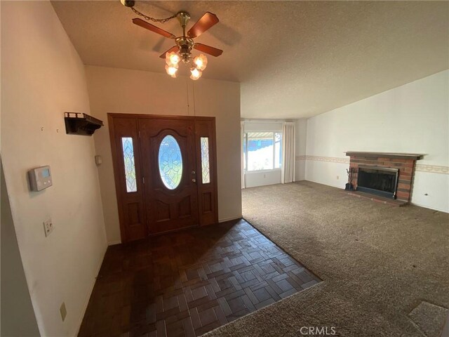 carpeted entrance foyer with ceiling fan, a textured ceiling, and a brick fireplace