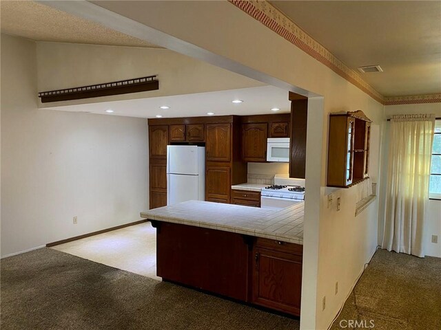 kitchen featuring tile countertops, white appliances, carpet floors, and vaulted ceiling