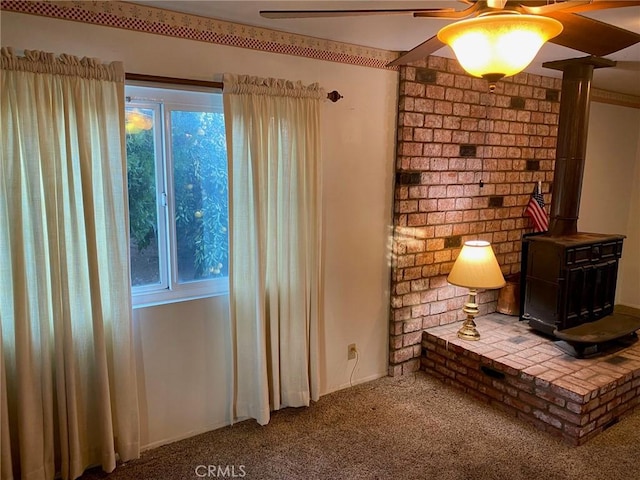 interior space featuring carpet flooring, ceiling fan, and a wood stove