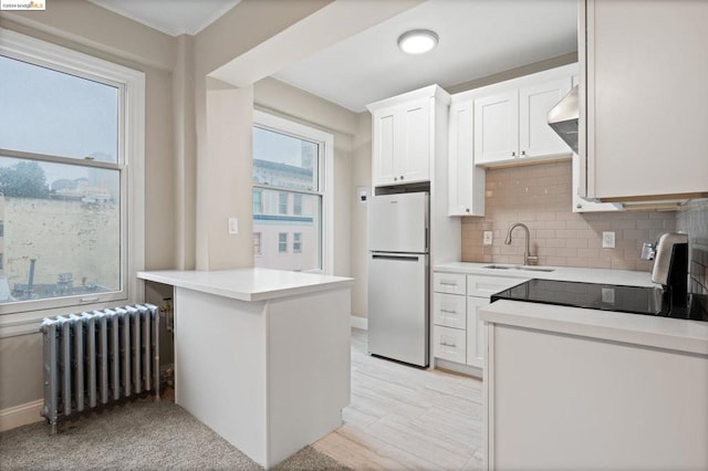 kitchen with radiator, sink, tasteful backsplash, white refrigerator, and white cabinets