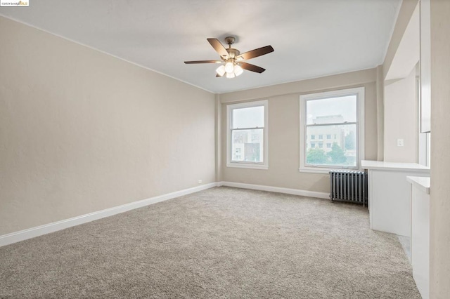 unfurnished room with light carpet, radiator heating unit, and ceiling fan