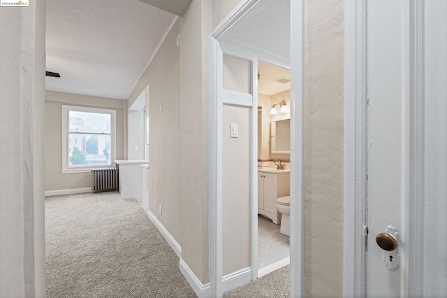 corridor with carpet floors, radiator, and sink