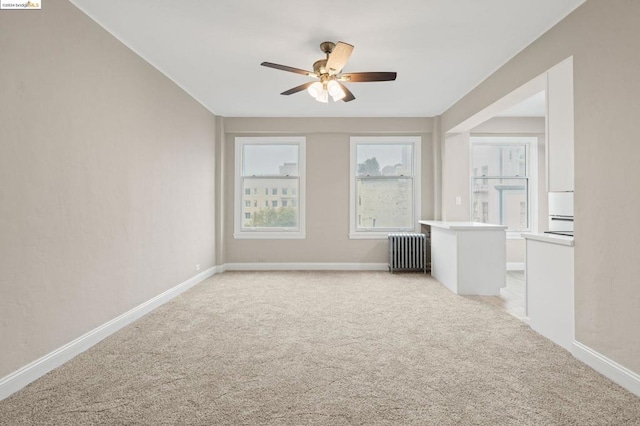 carpeted spare room featuring radiator and ceiling fan