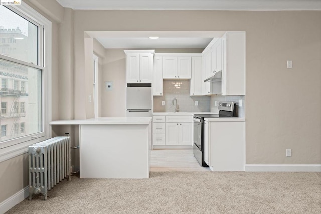 kitchen with stainless steel range with electric cooktop, white cabinets, white fridge, light colored carpet, and radiator heating unit