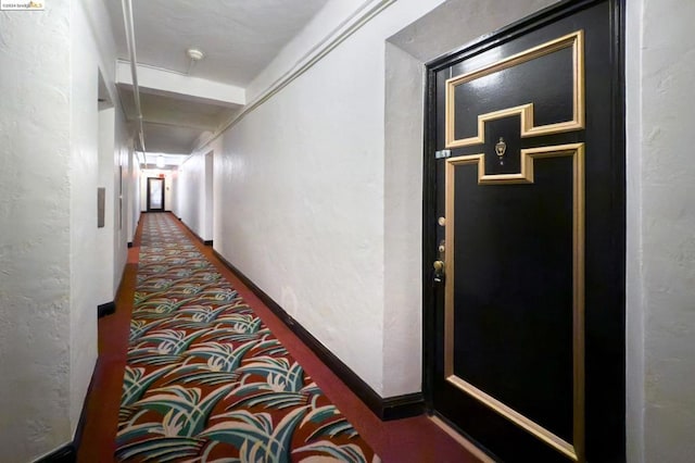 hall featuring dark colored carpet