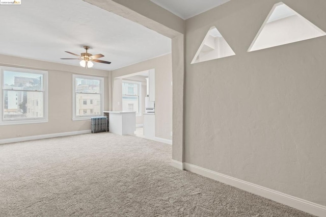 unfurnished room featuring carpet flooring, radiator, and ceiling fan