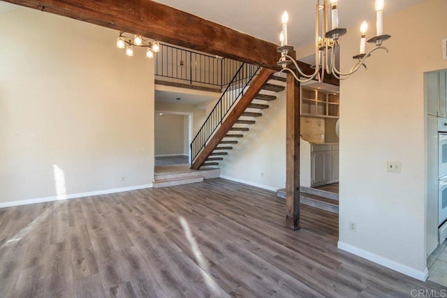 unfurnished living room featuring a chandelier, beam ceiling, and hardwood / wood-style flooring