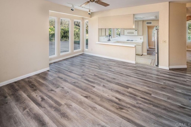 unfurnished living room with ceiling fan, sink, track lighting, and hardwood / wood-style floors