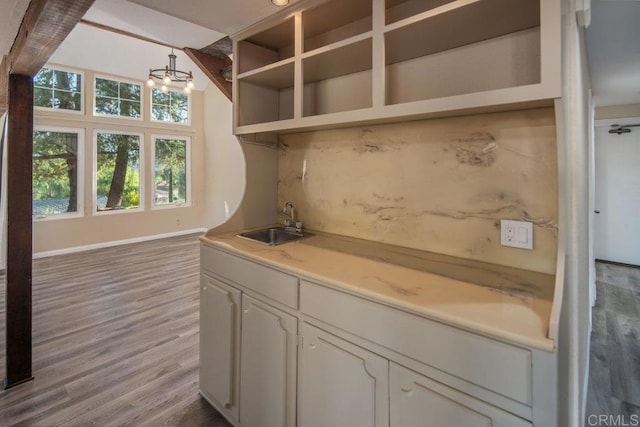 bar with white cabinetry, light hardwood / wood-style floors, sink, hanging light fixtures, and a notable chandelier