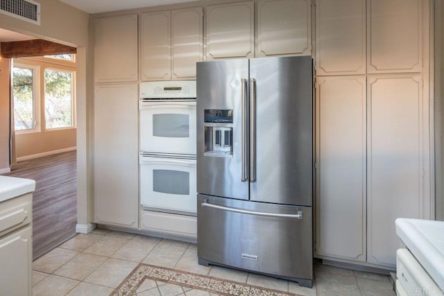 kitchen with stainless steel refrigerator with ice dispenser, light tile patterned floors, and double oven