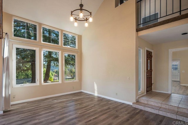 unfurnished dining area with an inviting chandelier, dark hardwood / wood-style flooring, and a high ceiling