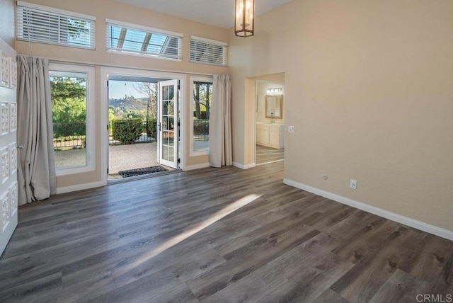 interior space with dark wood-type flooring, a chandelier, and a high ceiling