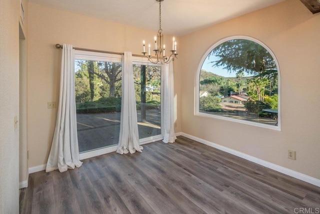 unfurnished dining area featuring dark wood-type flooring and an inviting chandelier