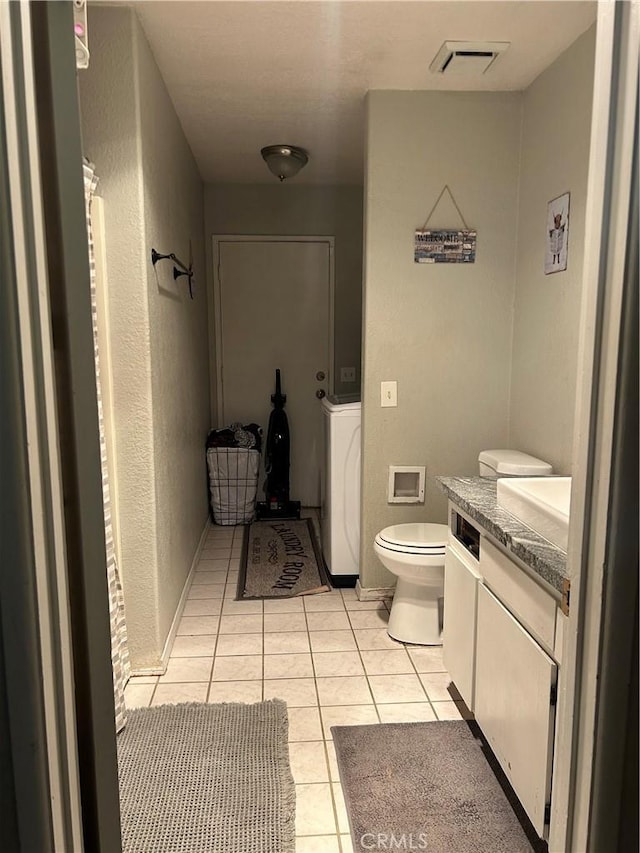 bathroom featuring tile patterned flooring, washer / dryer, vanity, and toilet