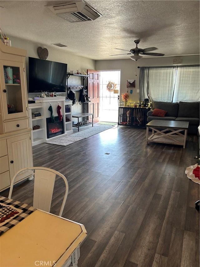 living room featuring ceiling fan, dark hardwood / wood-style flooring, and a textured ceiling