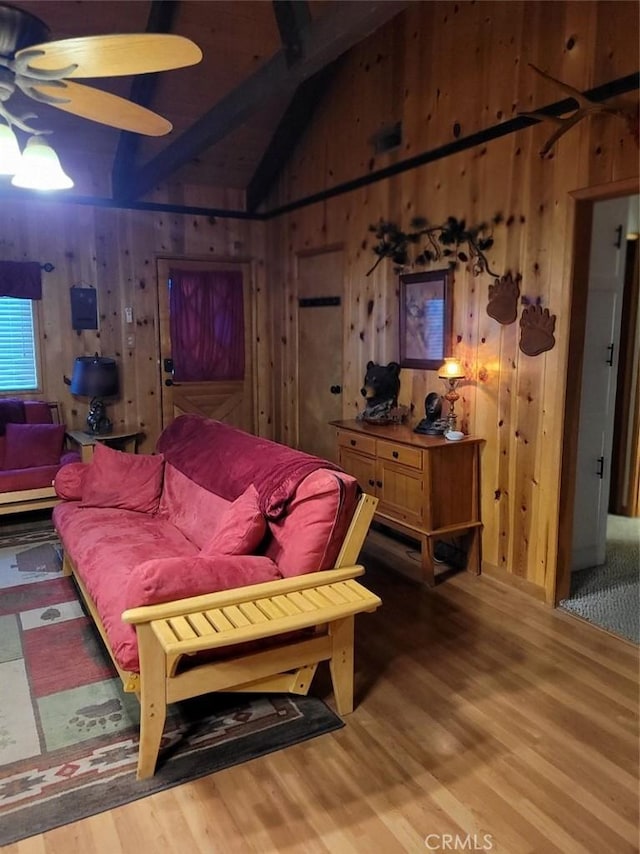 living room with wood-type flooring, lofted ceiling with beams, and wood walls