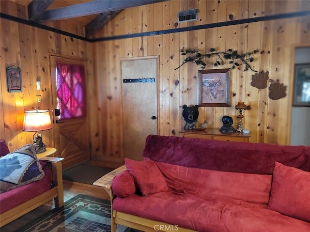 living room with beamed ceiling, wood walls, and dark wood-type flooring