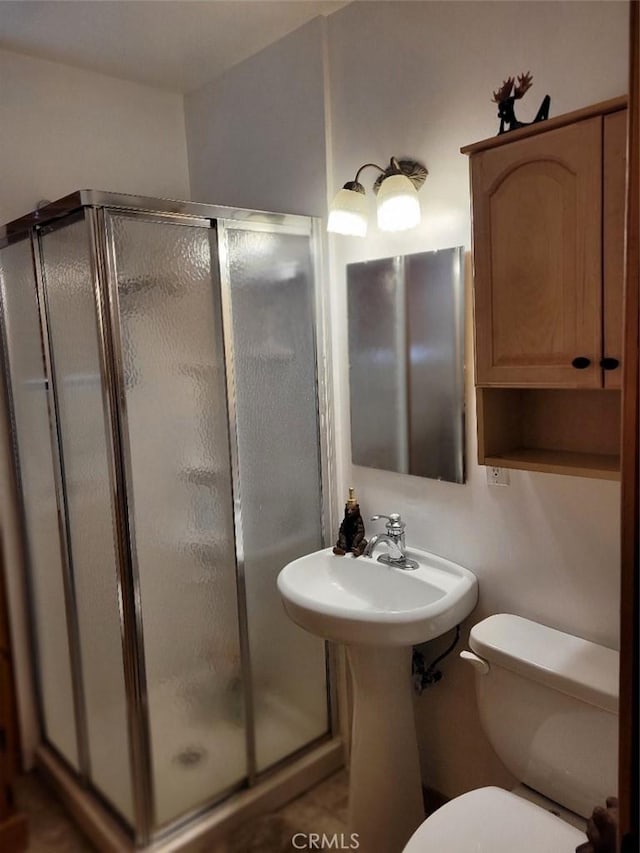 bathroom featuring toilet, a shower with door, and tile patterned flooring