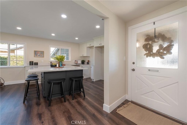 kitchen featuring a kitchen bar, white cabinetry, dark hardwood / wood-style flooring, and a center island