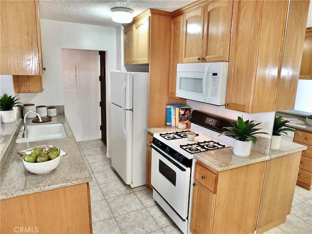 kitchen with sink, light tile patterned floors, white appliances, light stone countertops, and a textured ceiling