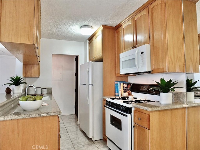 kitchen featuring sink, light tile patterned floors, white appliances, light stone counters, and a textured ceiling