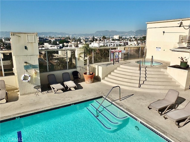 view of swimming pool featuring a mountain view, a community hot tub, and a patio area