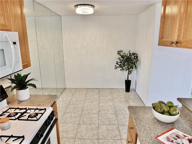 kitchen with light stone counters, white appliances, and light tile patterned flooring