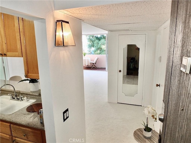 hall featuring a paneled ceiling and sink