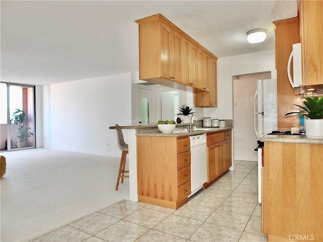 kitchen with sink, white appliances, a breakfast bar area, a textured ceiling, and kitchen peninsula