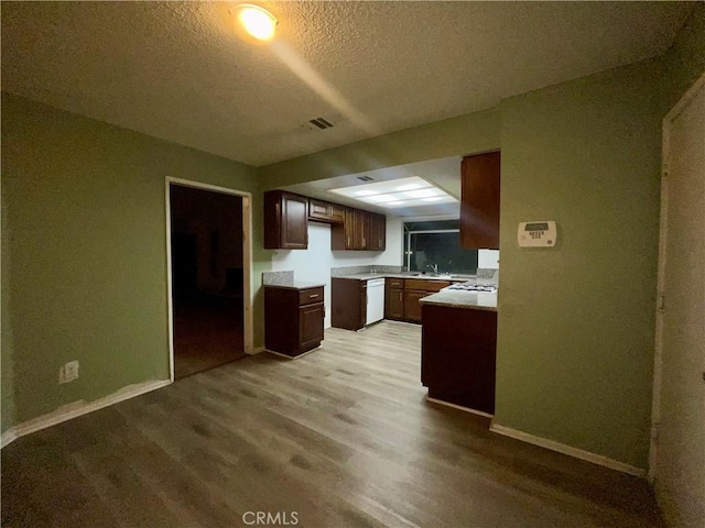 kitchen featuring dishwasher, a textured ceiling, light hardwood / wood-style floors, and sink