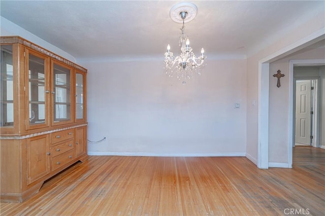 unfurnished dining area with an inviting chandelier and light hardwood / wood-style flooring