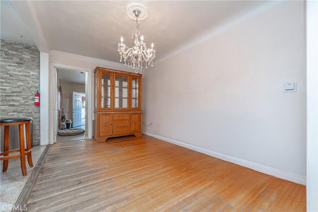 unfurnished dining area featuring a chandelier and light wood-type flooring