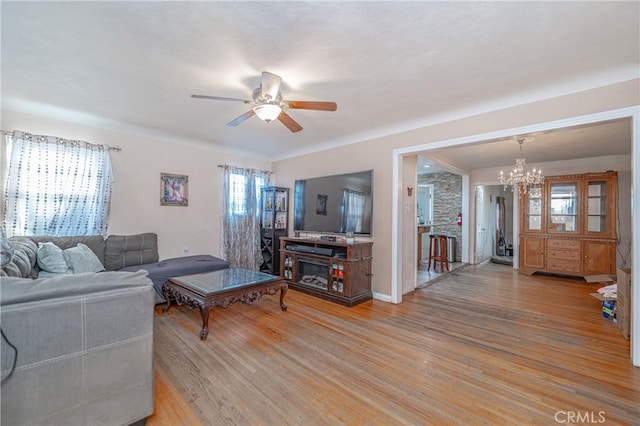 living room featuring ceiling fan with notable chandelier, light hardwood / wood-style flooring, and a healthy amount of sunlight