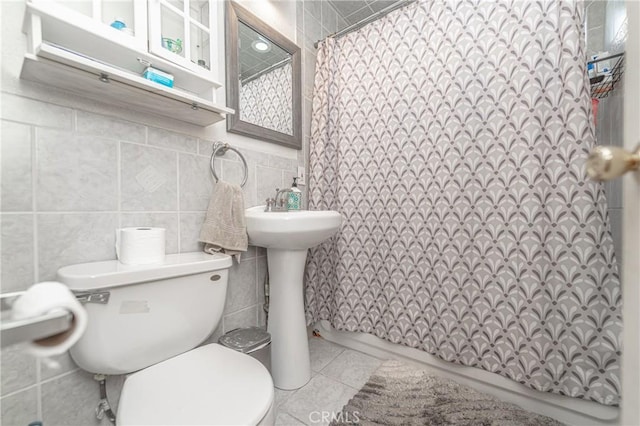 bathroom with tile patterned floors, curtained shower, tile walls, and toilet