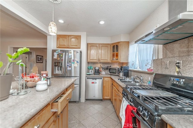 kitchen with sink, wall chimney exhaust hood, decorative backsplash, appliances with stainless steel finishes, and decorative light fixtures