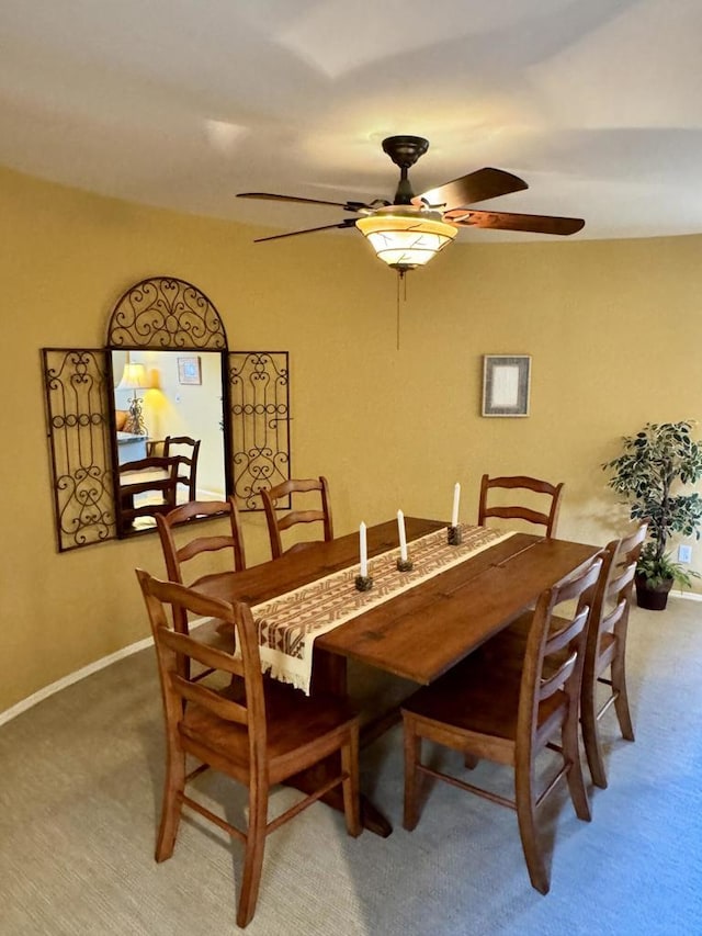 carpeted dining room with ceiling fan