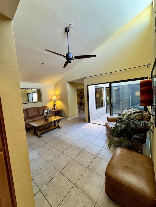 living room featuring ceiling fan, light tile patterned floors, and vaulted ceiling