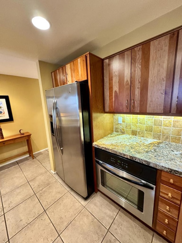 kitchen featuring light tile patterned floors, light stone countertops, backsplash, and appliances with stainless steel finishes