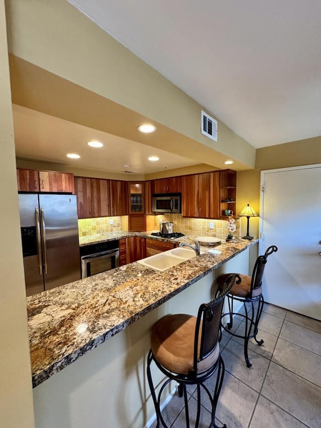 kitchen featuring kitchen peninsula, backsplash, appliances with stainless steel finishes, and dark stone counters