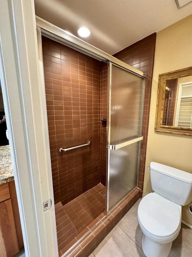 bathroom featuring tile patterned floors, vanity, a shower with shower door, and toilet