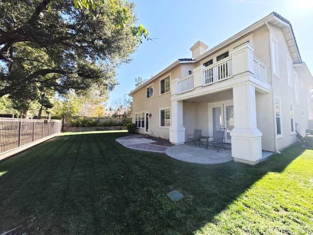 rear view of house with a yard, a patio, and a balcony