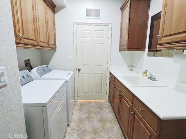 laundry area featuring washer and clothes dryer, sink, light tile patterned flooring, and cabinets