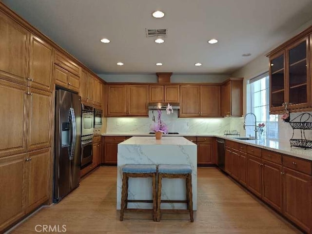 kitchen with a kitchen breakfast bar, a kitchen island, stainless steel appliances, and light wood-type flooring