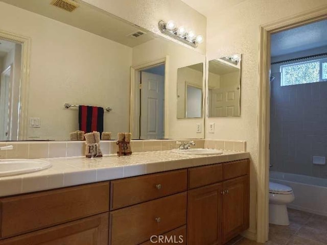 full bathroom featuring tile patterned floors, vanity, tiled shower / bath combo, and toilet