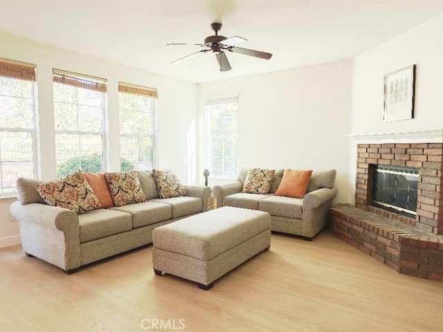 living room featuring a brick fireplace, light hardwood / wood-style flooring, and ceiling fan