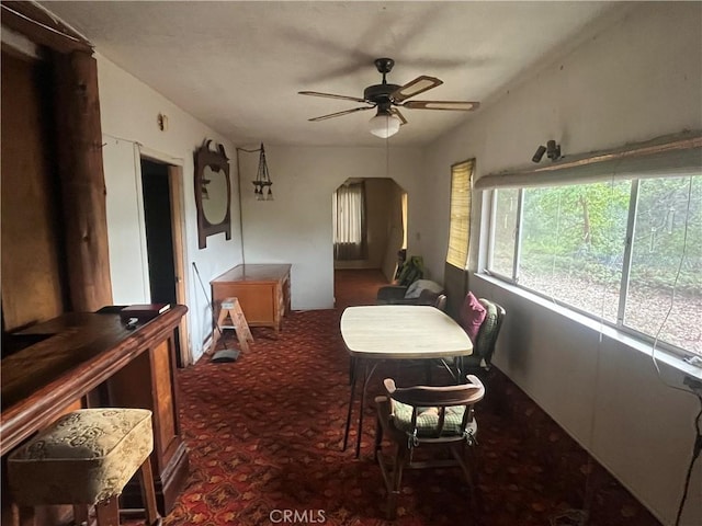 dining area featuring a ceiling fan, carpet, and arched walkways